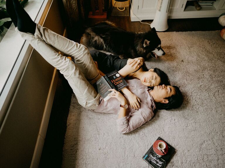 To-be-weds snuggling on the floor with their dog.