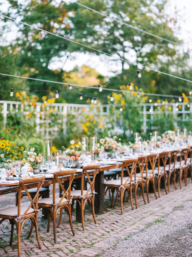outdoor reception with wood farm table and cross-back chairs