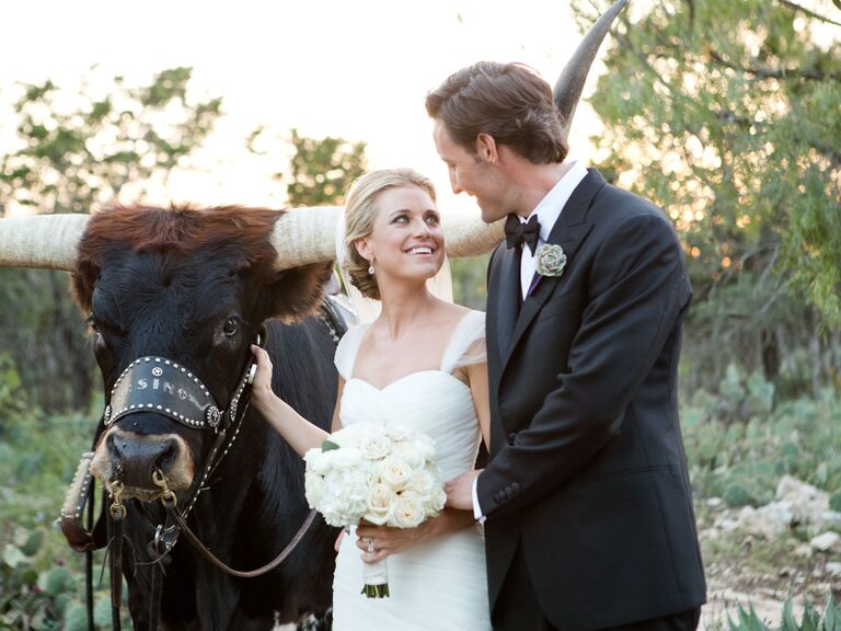 Newlyweds pose with a longhorn at their ranch-style wedding. 