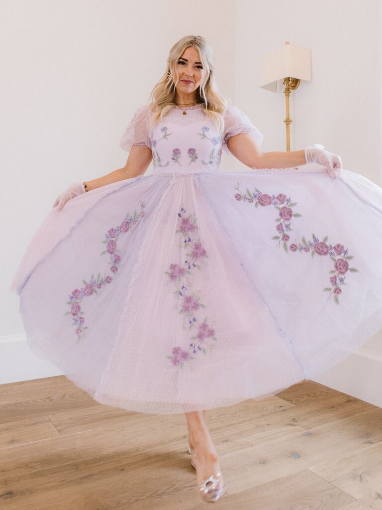 Model wears a light purple gown with floral embroidery. 
