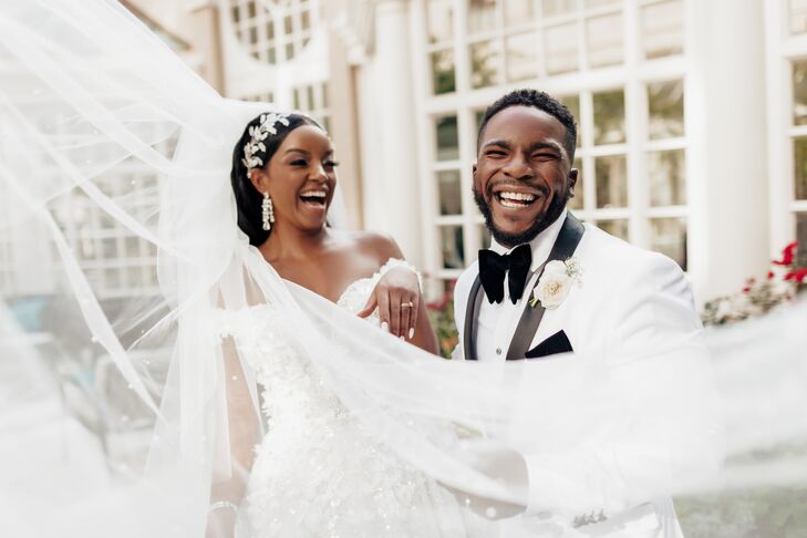 Bride With Ornate Crystal Headpiece, Flowing Veil and Groom in White Tuxedo Laughing