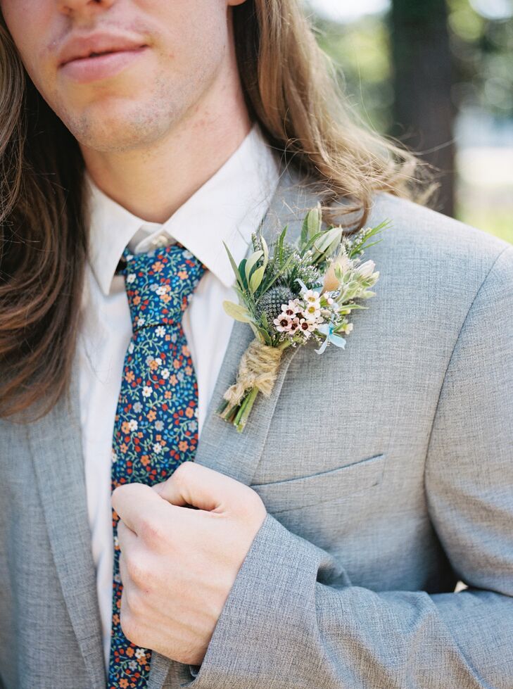 Groom shows off his pastel boutonniere inspired by their garden party morning wedding, featuring thistles, wildflowers, greenery, and a rustic touch.