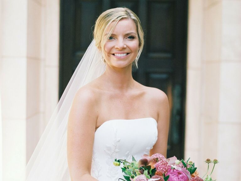 Bride wears her hair pulled back with wispy pieces framing her face. 