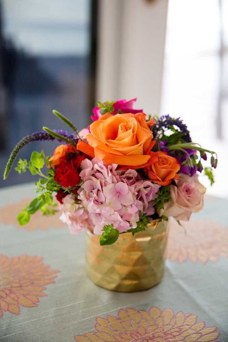 "I like to paint with bright, clean colors," Amy says. "We added in a touch of some other colors to make the arrangements pop." Each cocktail table was paired with a fun floral linen and bright centerpieces of orange, red and pink roses, pink hydrangeas, purple veronica and greenery. Each was designed by Garden District-Naples.