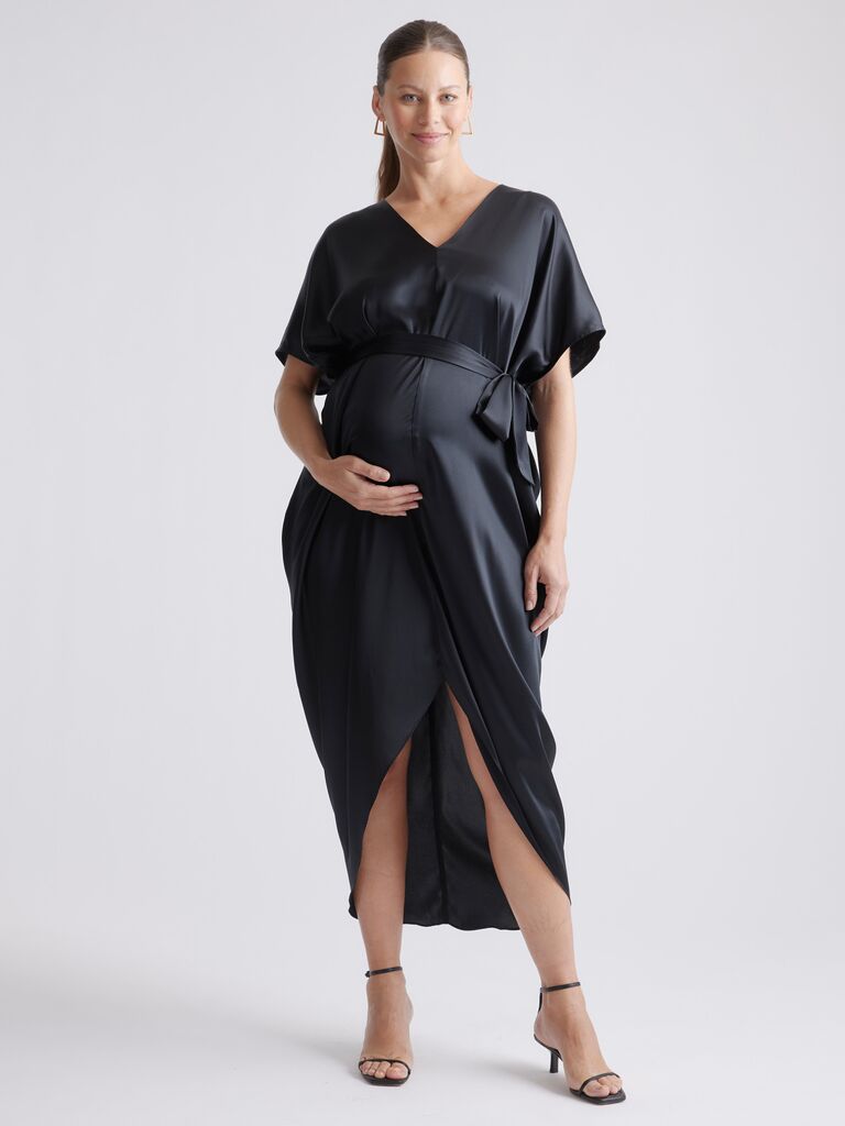 Model wears a mid-length black silk dress. 