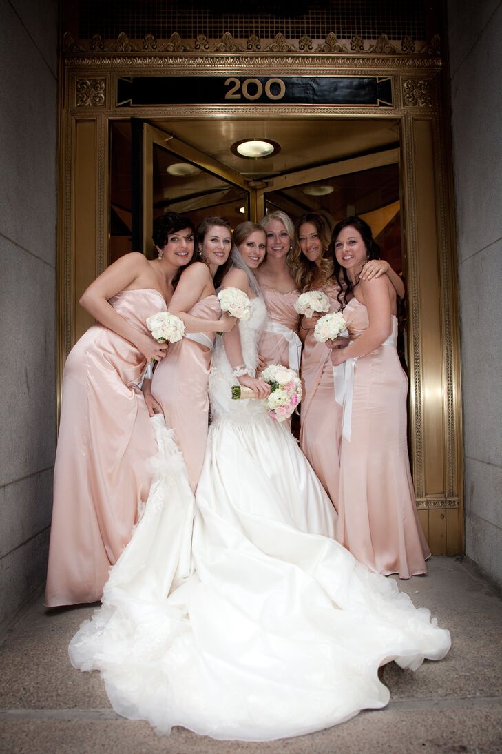 Kelly’s nine-foot train was manned by five bridesmaids dressed in silk charmeuse blush gowns. Silk ivory satin ribbons were tied at the waist of each bridesmaid.