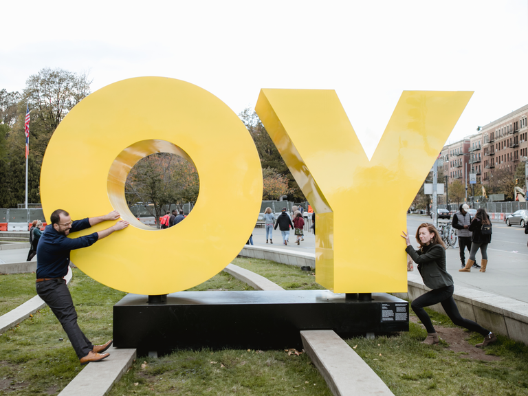 Couple poses with sculpture outside of an art museum. 