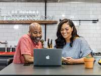Engaged couple making wedding registry checklist on laptop