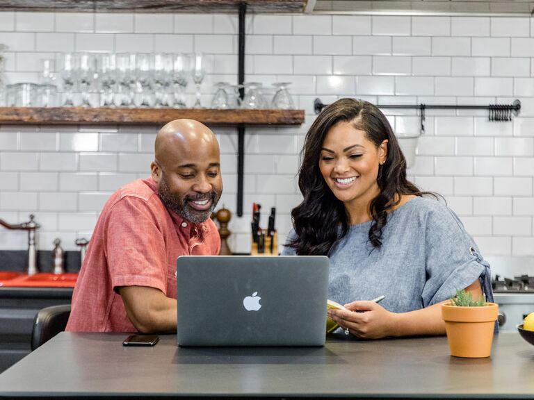 Engaged couple making wedding registry checklist on laptop