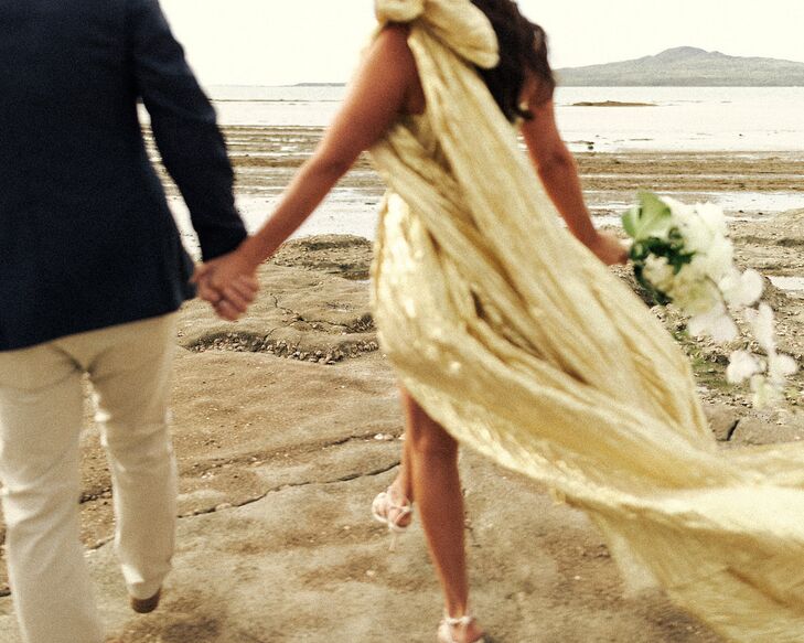 Artistic Photo of Bride in Gold Dress and Cascading Bouquet on Beach With Groom