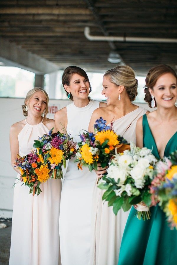Bridesmaids holding colorful sunflower bouquets