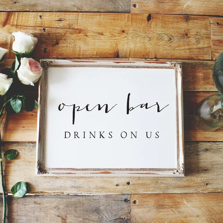 rustic white sign with black lettering that says 'open bar drinks on us sign' for wedding bar sign