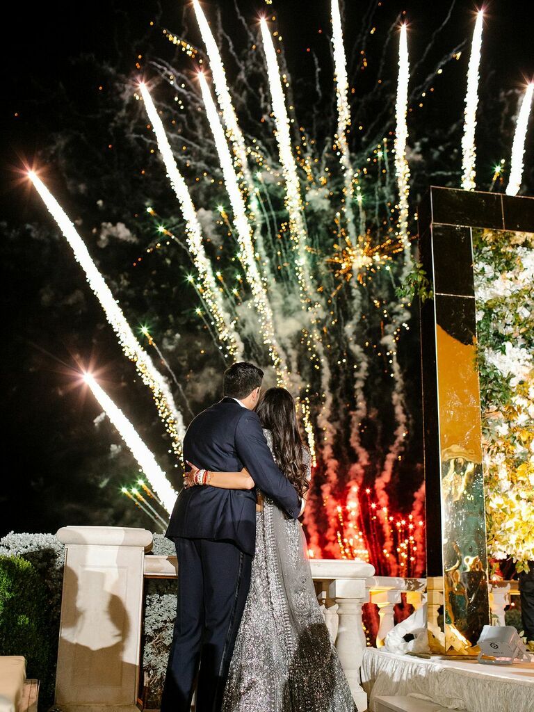 Bride and groom watch large wedding firework display. 