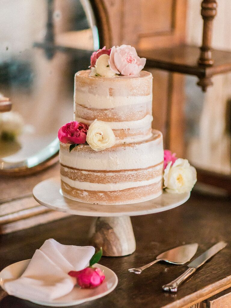 two tier semi naked wedding cake with pink peonies and white ranunculus