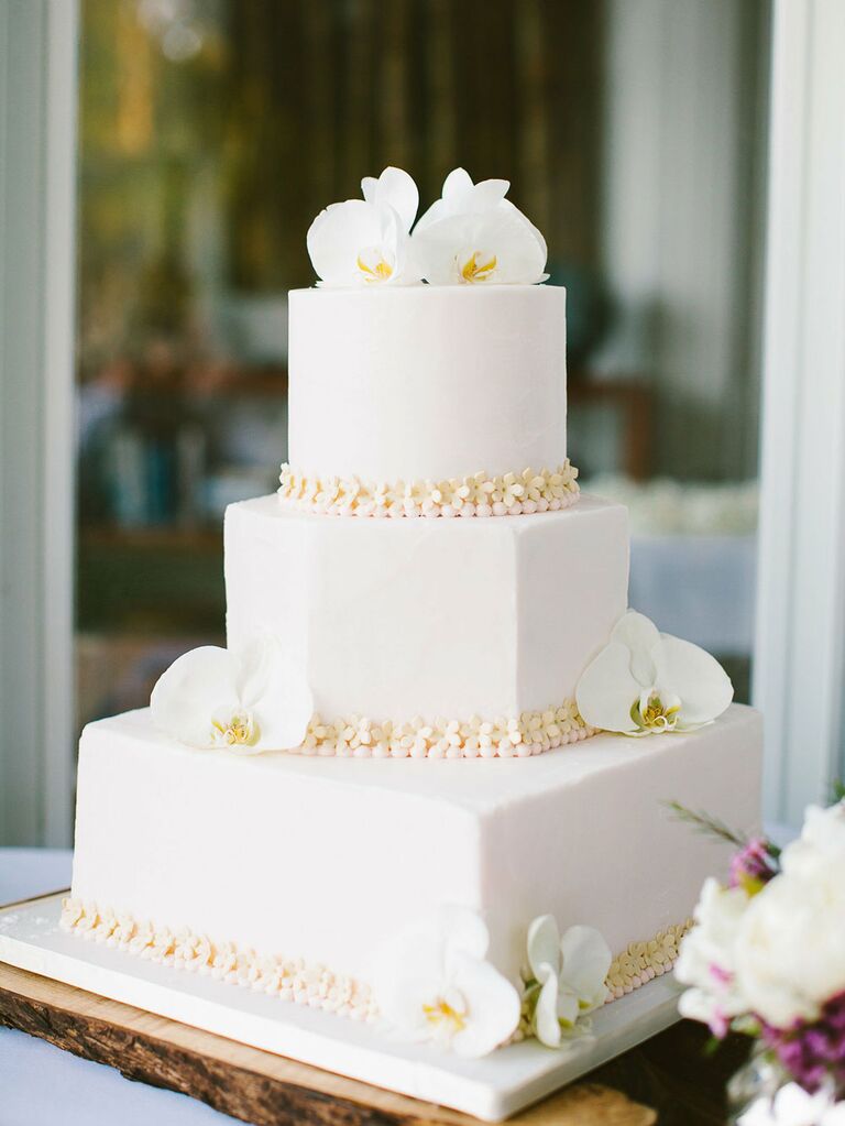 Three-tier white beach wedding cake with tropical orchid florals