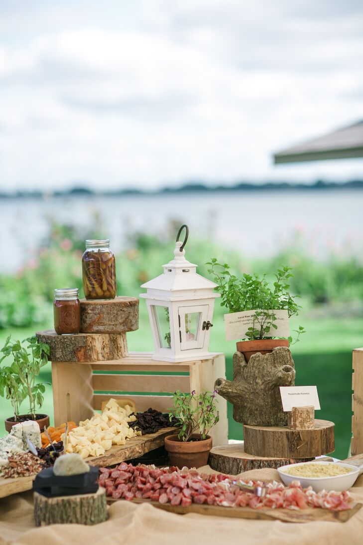 An assortment of meats and cheeses was arranged on a table, surrounded by rustic slabs of wood and lanterns.