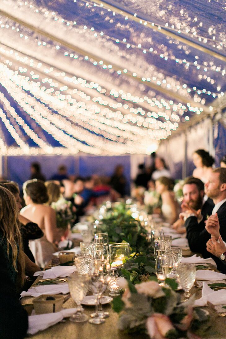 The long reception tables were topped with a runner of vintage library card boxes filled with greenery. "Everything looked so whimsical mixed with the twinkle lighting and the clear top tent," says Jenn. "I felt like we were in a secret garden."