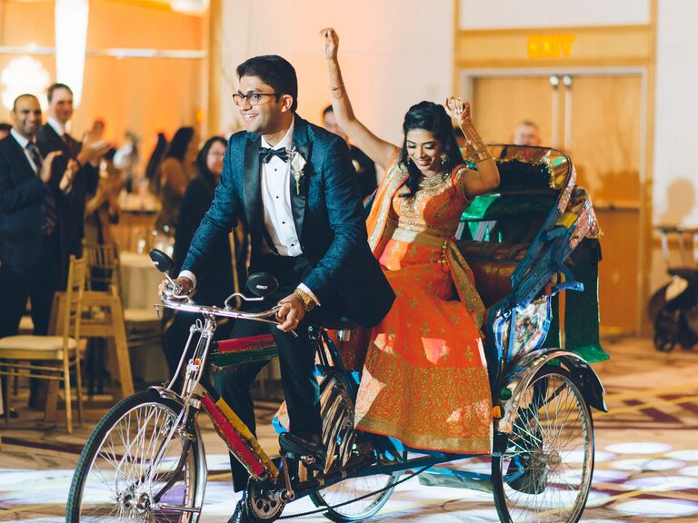 Groom carries bride in a colorful rickshaw.