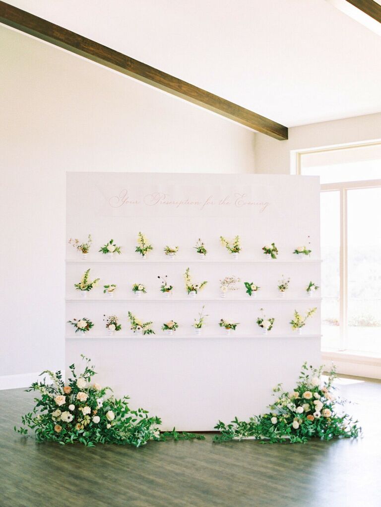 Pharmacy-inspired escort card display with mini flower arrangements