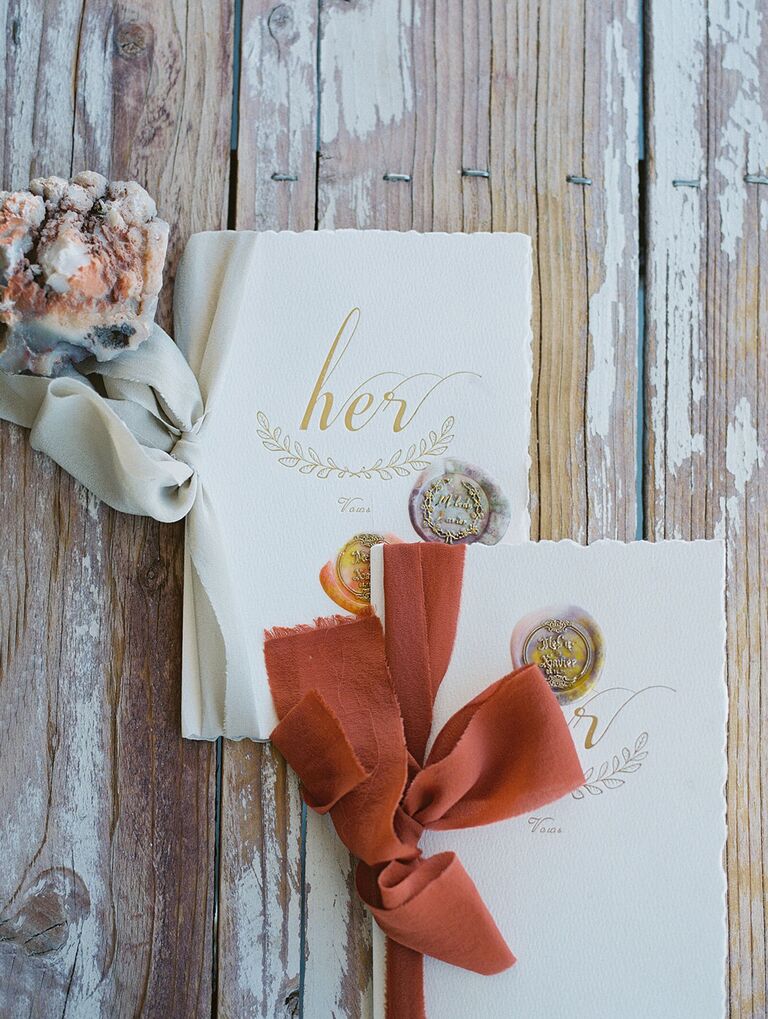 wedding vow booklets decorated with wax stamps and tied with rust orange and ivory ribbons in 2022 wedding colors