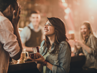 Woman proposing to man in public at a bar