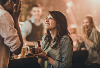 Woman proposing to man in public at a bar