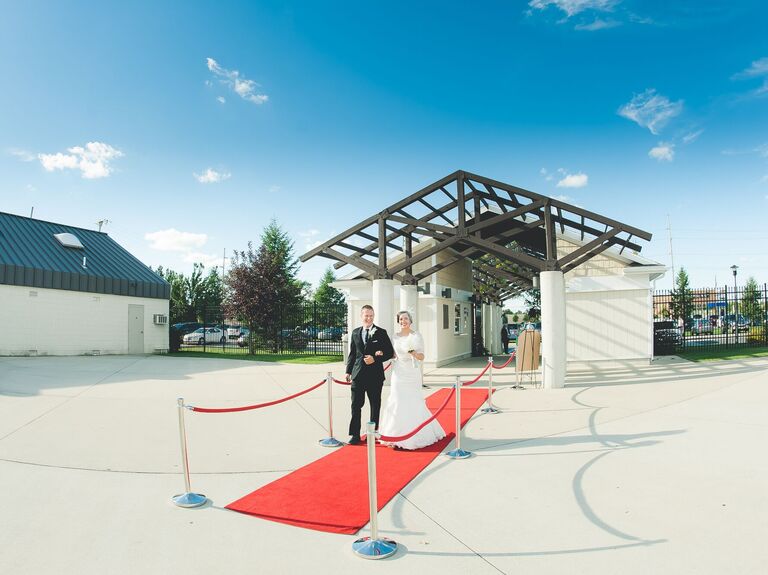 Bride and groom walking down a red carpet.