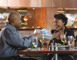 Husband giving wife anniversary gift while out to eat for dinner