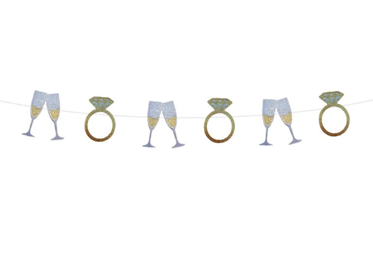 A glittery bunting with rings and champagne glasses.