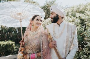 Bride in Pink Outfit, Veil Holds Parasol With Groom in Sherwani and Sword