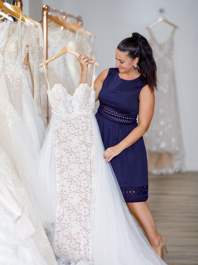 wedding dress shop owner holding wedding dress