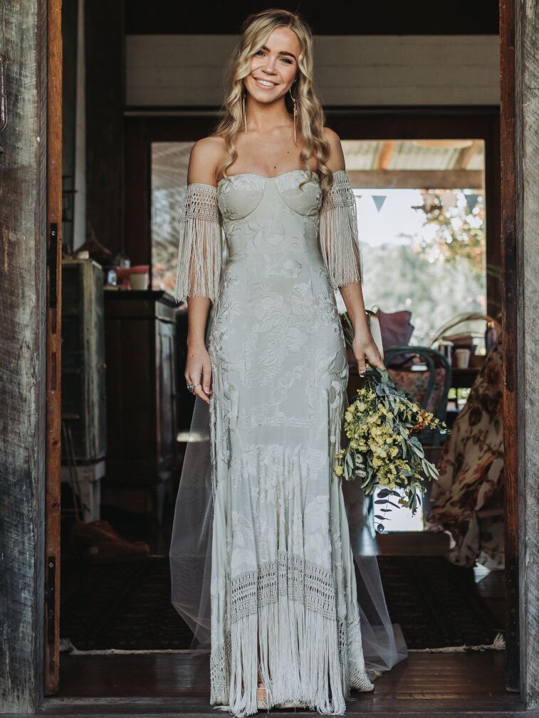 Model wears a unique off the shoulder wedding dress. 