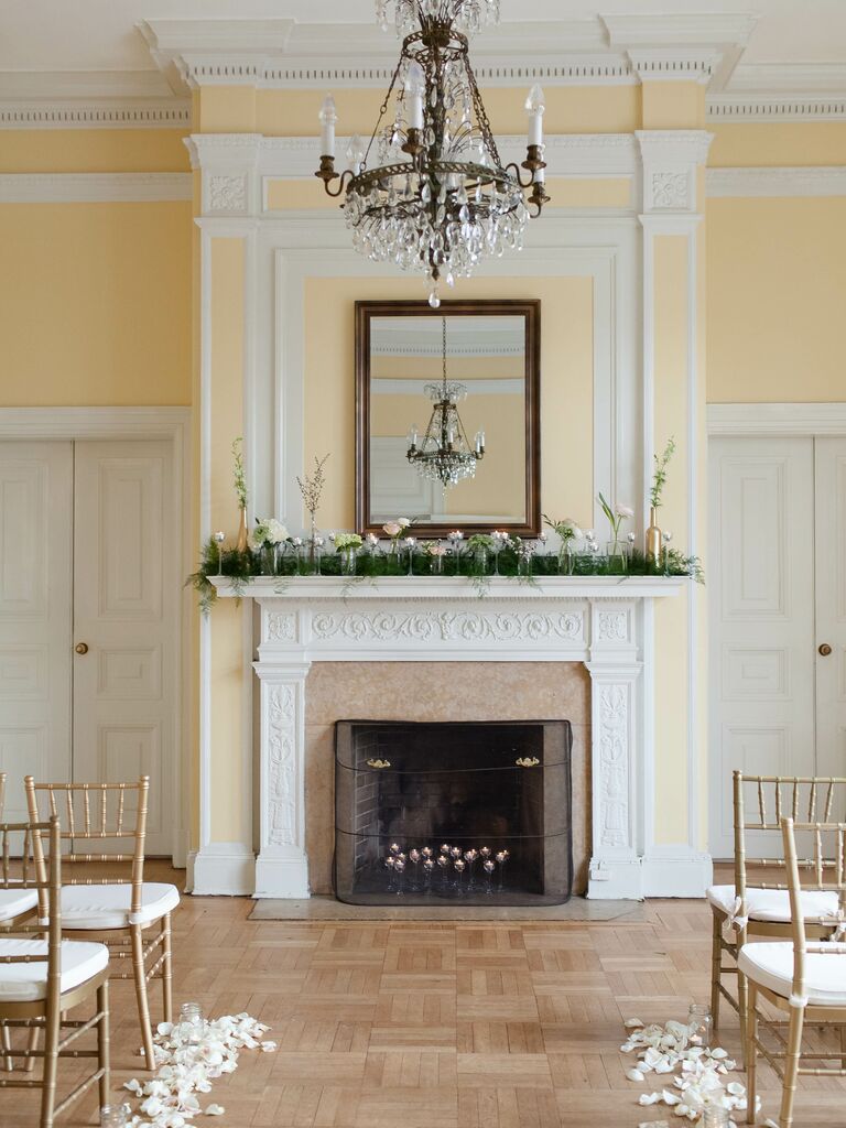 elegant wedding fireplace decor with greenery and fresh flowers in small glass bud vases along the mantel