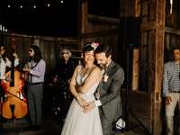 Couple dancing with standing bass in background in rustic barn setting