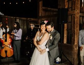 Couple dancing with standing bass in background in rustic barn setting