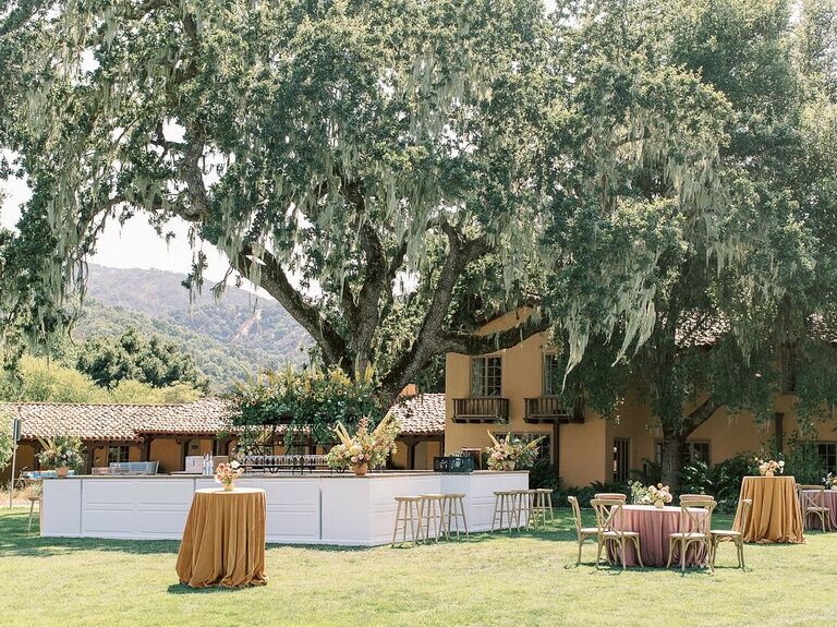 White outdoor bar space beneath oak tree and Spanish moss.