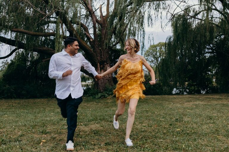 Couple holding hands and running through field