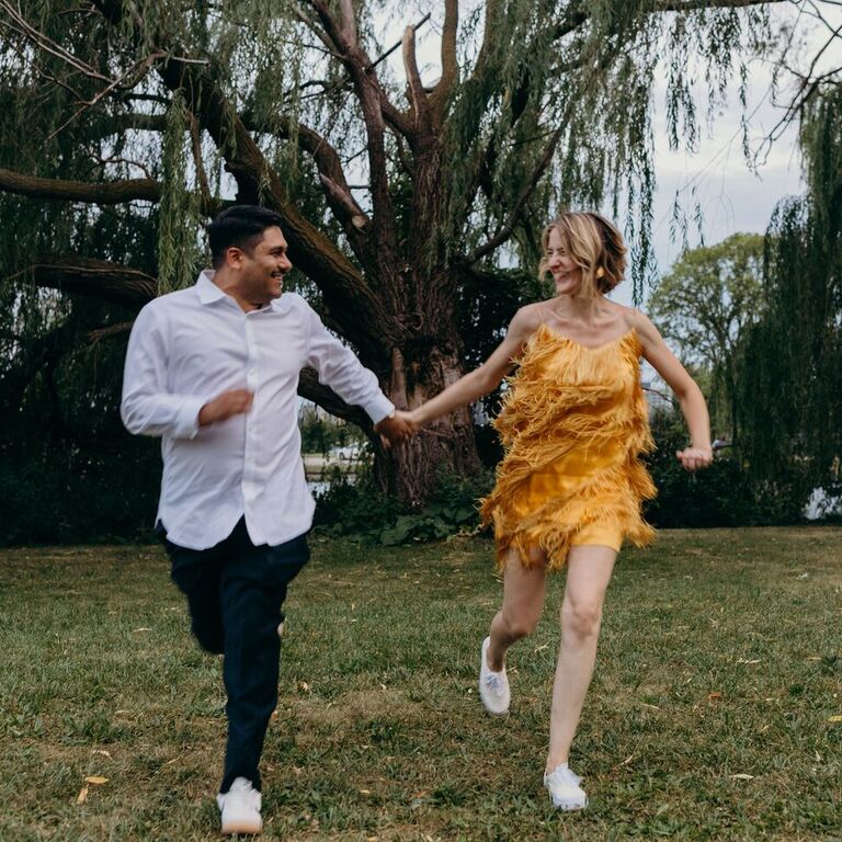 Couple holding hands and running through field