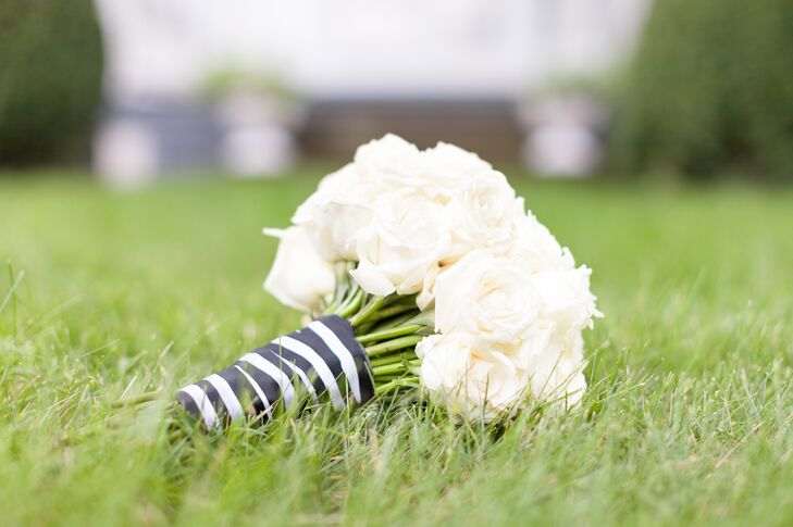 Anna held an elegant, round bouquet filled with ivory roses. The roses were tied together around the stems by a black-and-white-striped wrap.