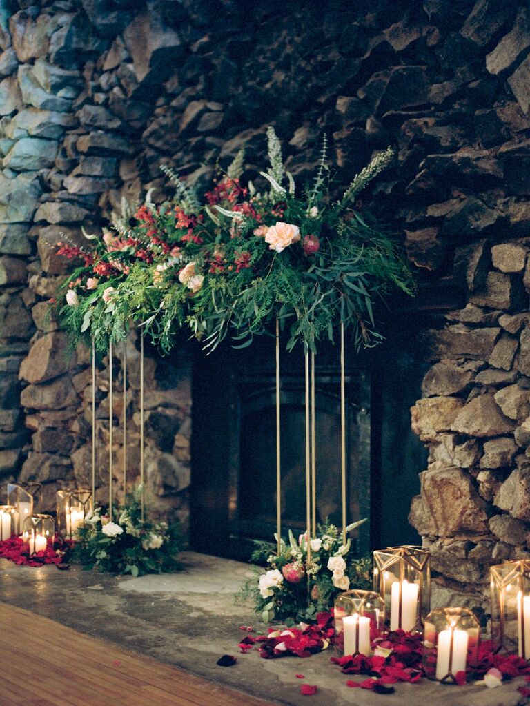 winter wedding fireplace decor with greenery and red flowers