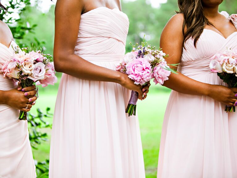 Bridesmaids hold pale pink bouquets.