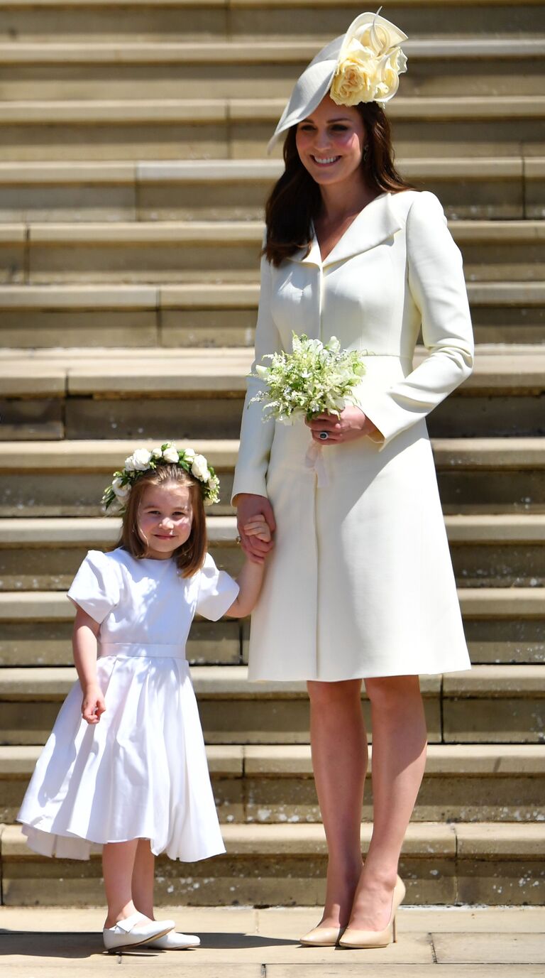Princess Charlotte smiles for the camera while holding hands with the flower girl. 