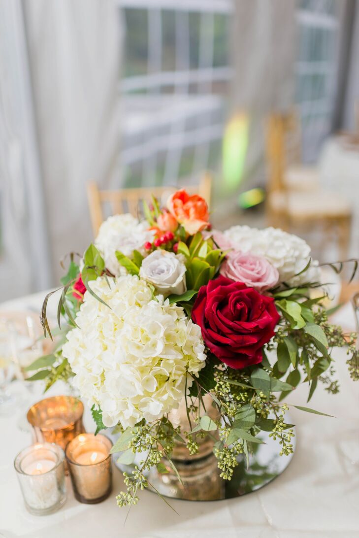 Romantic arrangements of white hydrangeas and red, white and pink roses stood in the center of the round tables at the reception.