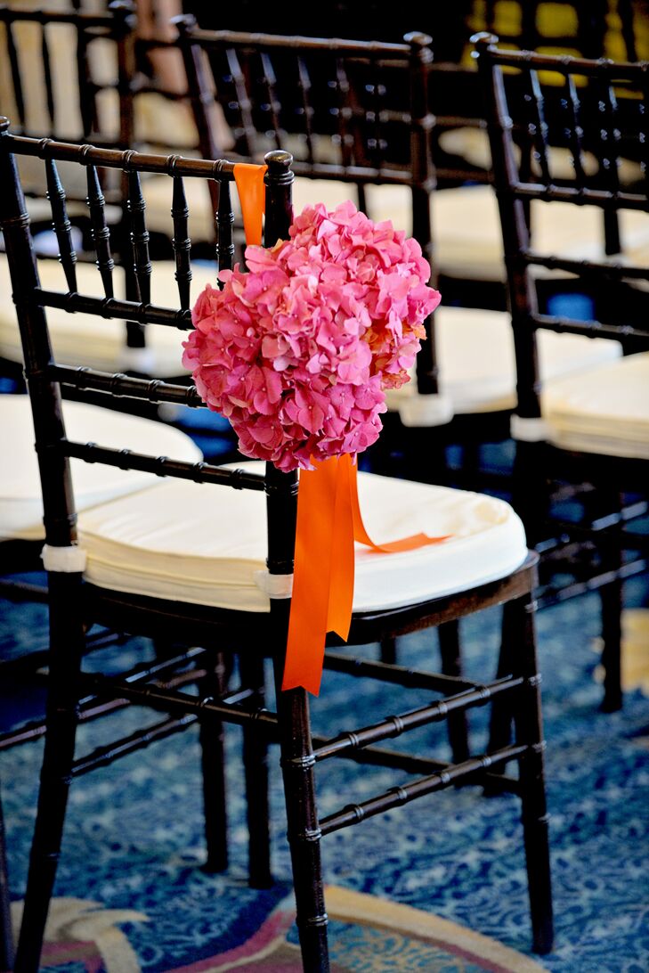 With a spectacular waterfront venue right on Boston Harbor, Ashley and Matthew decided to let the views take center stage and kept the ceremony decor simple. Black chiavari chairs lined the ceremony aisle, with alternating rows boasting bright bunches of pink hydrangeas accented with vibrant orange bows.
