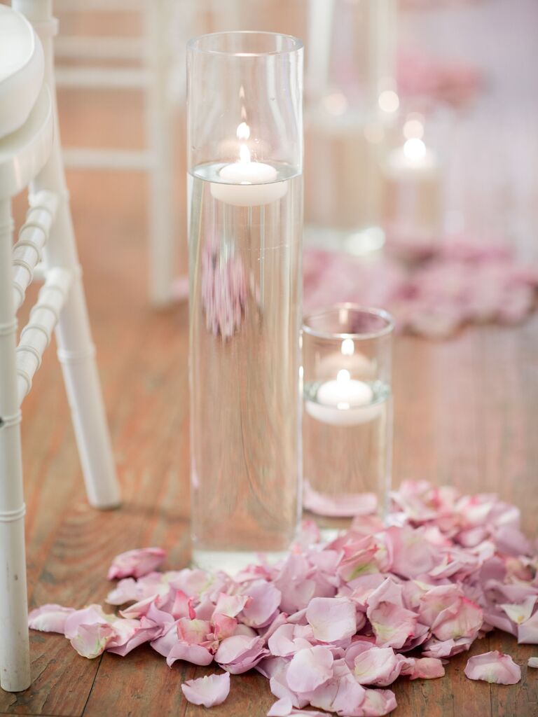 wedding ceremony aisle marker with pastel pink rose petals and floating candles in glass vases