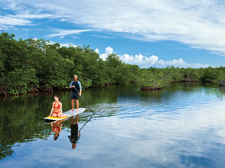 Man rowing a stand up paddleboard with woman on the front
