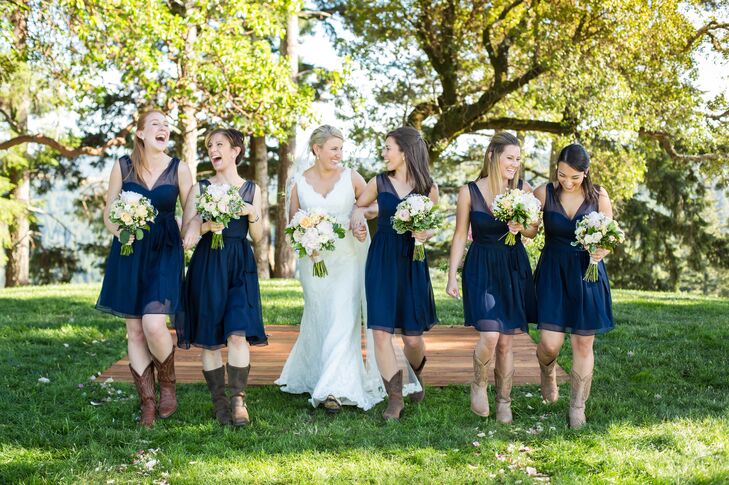 Allyson chose elegant A-line dresses for her bridesmaids in a classic navy color that allow them to wear the dresses again with ease. For a touch of country charm, the girls paired the look with brown cowboy boots.