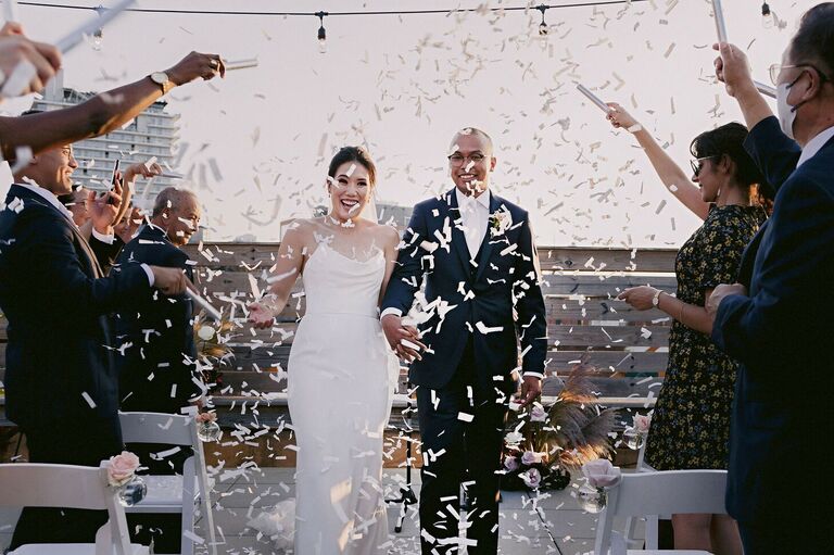 Couple exiting wedding ceremony with cascade of white confetti