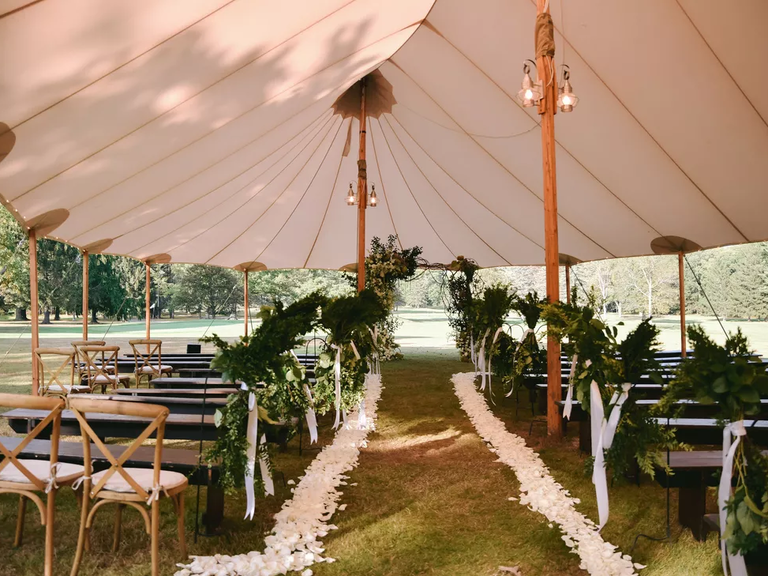 A beautiful tented ceremony site, complete with white flowers along the aisle.