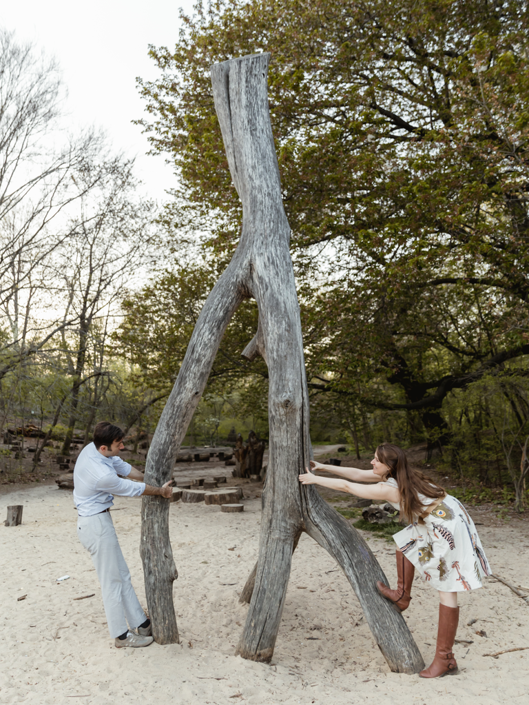 Couple pretends to break a large wishbone for an engagement photo. 